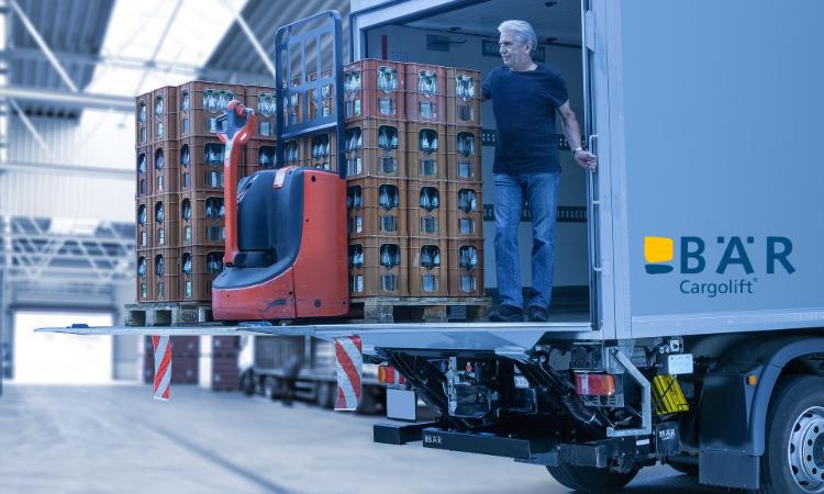 Chauffeur staat met meerdere drankpallets en een elektrische palletwagen op het platform van een Bär-laadklep