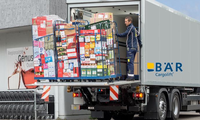 Vrachtwagenchauffeur laadt met behulp van de Bar Cargolift meerdere rolcontainers met levensmiddelen uit de vrachtwagen voor de levensmiddelenwinkel
